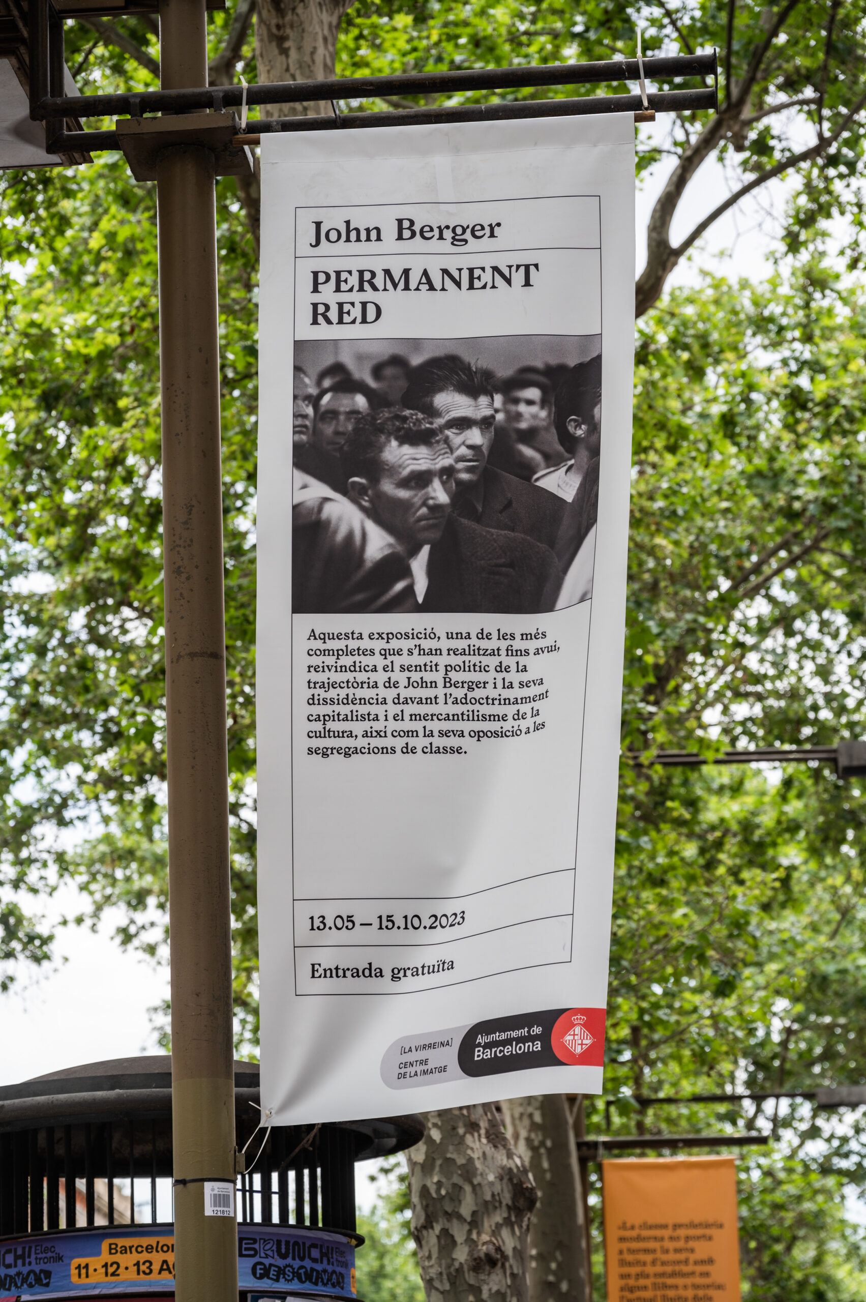Flag in trees on Las Ramblas announcing Permanent Red exhibition about John Berger at La Virreina Centre, Barcelona
